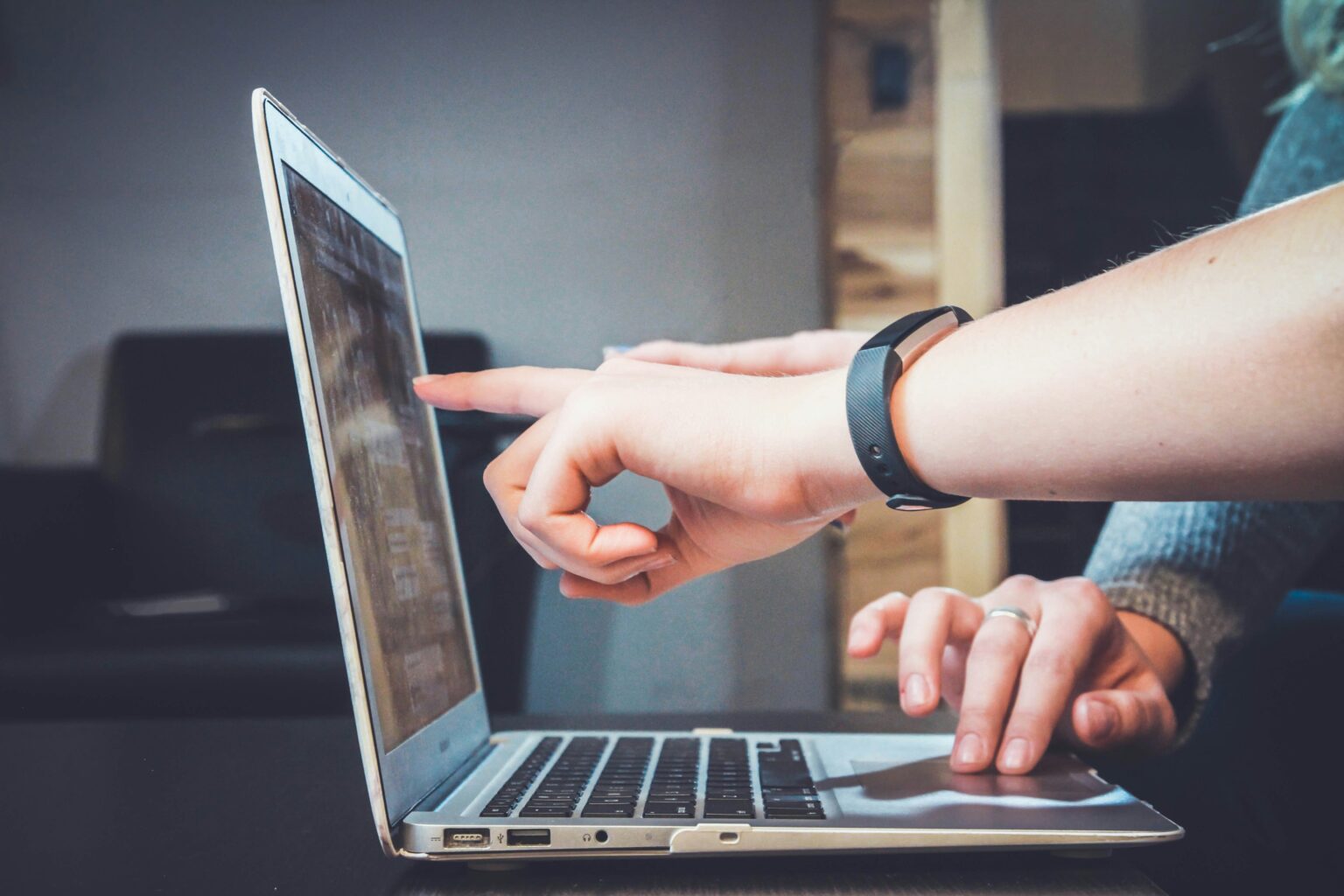 Person pointing at tablet screen wearing smartwatch